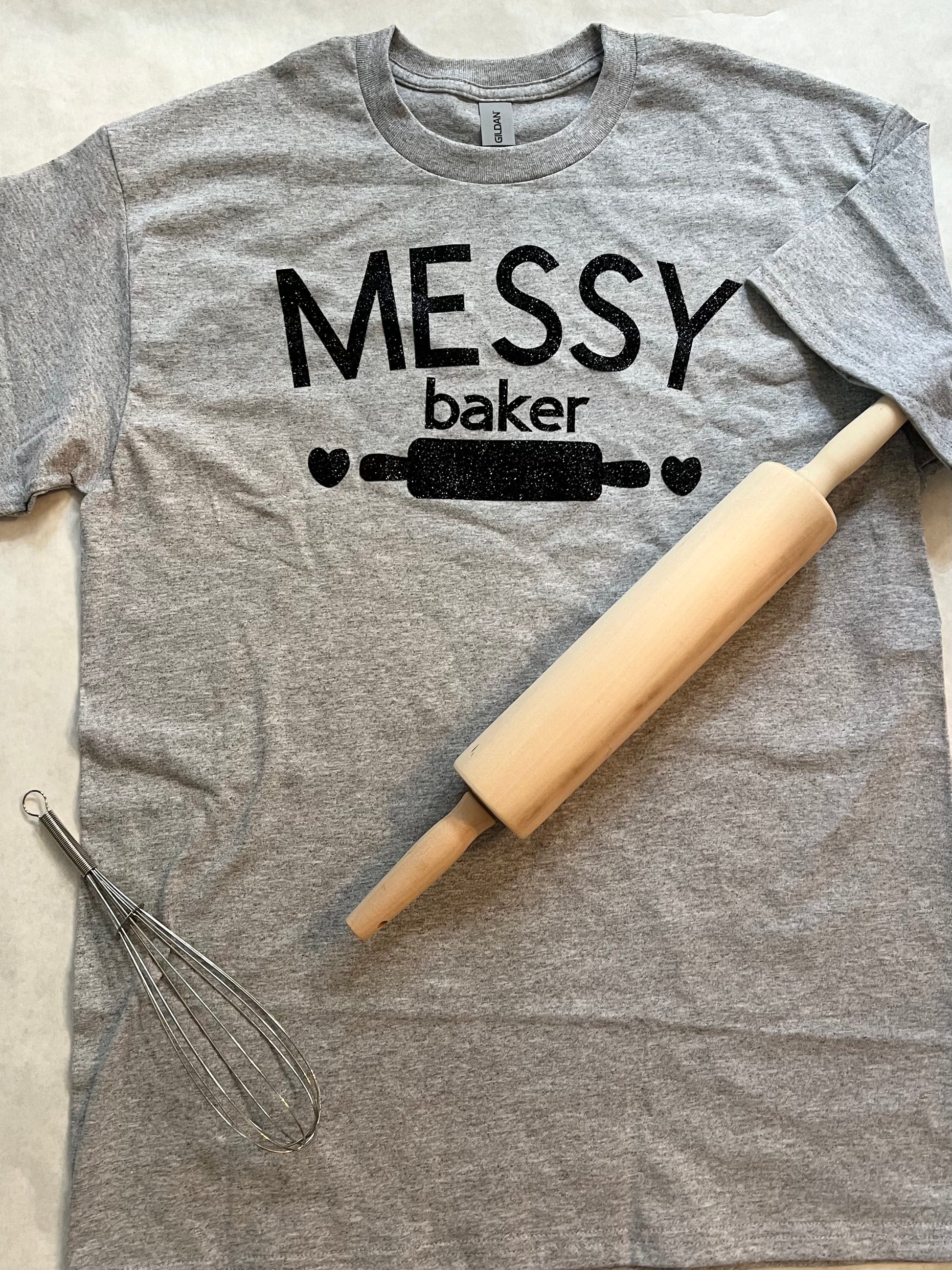 
HELLO FELLOW MESSY BAKERS ! 
The kitchen may be in shambles but your cakes and cookies  look and taste AMAZING. EMBRACE IT with this Messy Baker Heather grey tshirt